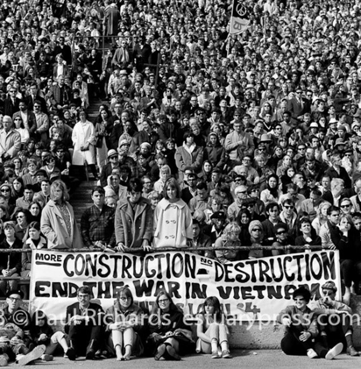 A 1960s stadium crowd in San Francisco holding a banner reading End the War in Vietnam